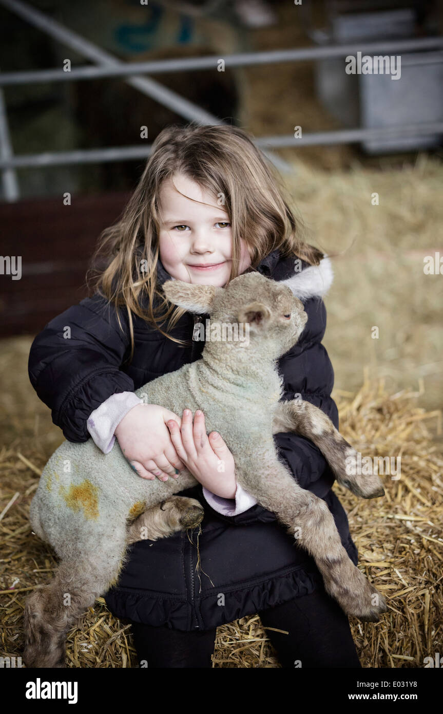 Una ragazza con un piccolo nuovo nato agnello. Foto Stock