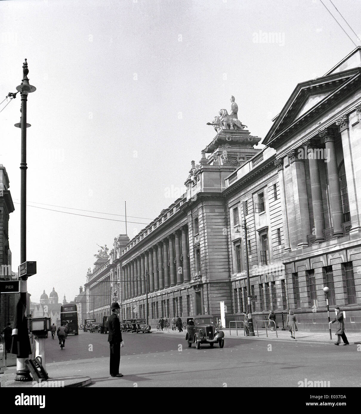 Degli anni Cinquanta, storico, una vista del grand victorian columed edifici di Kingston upon Hull City center come un poliziotto dirige il traffico di veicoli a motore. Vediamo automobili d'epoca e una società di trasporto motorbus doubledecker nella distanza. Foto Stock