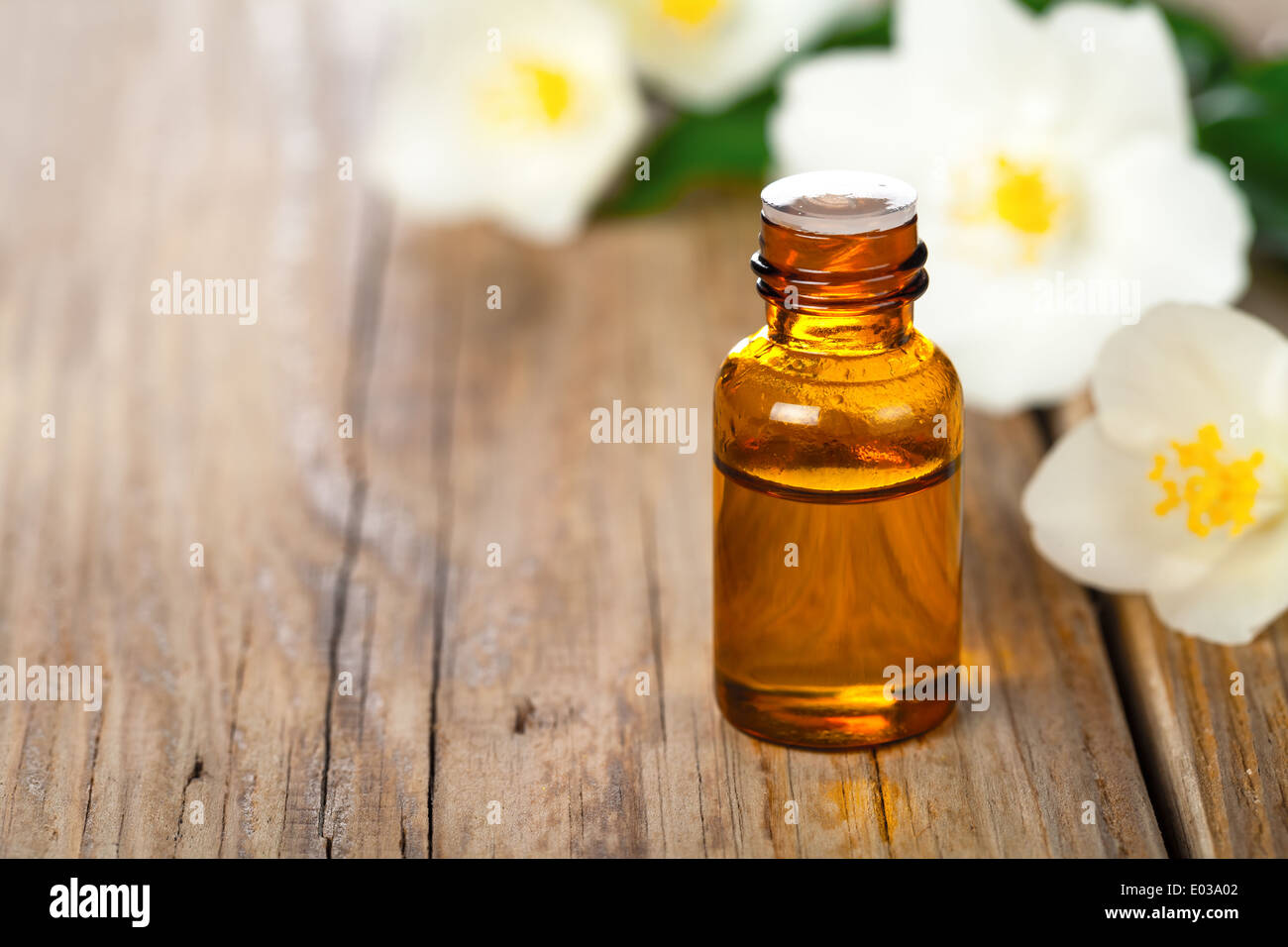 Jasmin olio essenziale con fiori di gelsomino sul tavolo di legno dello sfondo. Trattamento di bellezza. Spazio di copia Foto Stock
