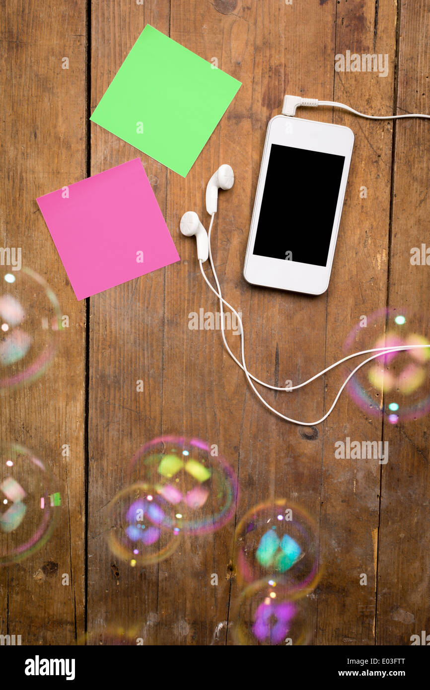 White smart phone e sticky notes su marrone sullo sfondo di legno Foto Stock