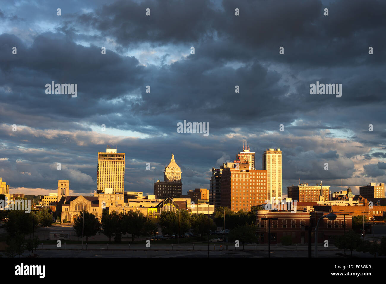 Sotto cieli minacciosi, lo skyline di Peoria, IL si illumina in tarda serata sole. Foto Stock