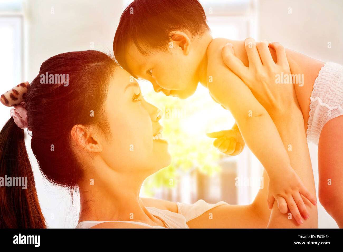 Felice madre holding adorabili bambini baby con sfondo di sunrise Foto Stock