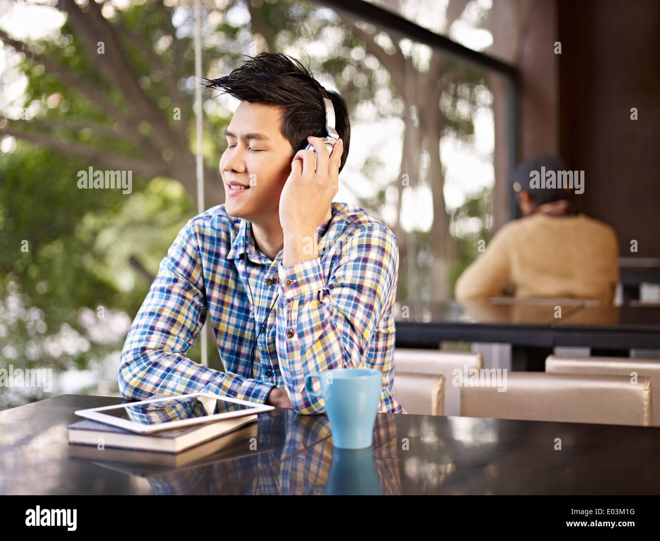 Giovane uomo ascoltare musica in coffee shop Foto Stock
