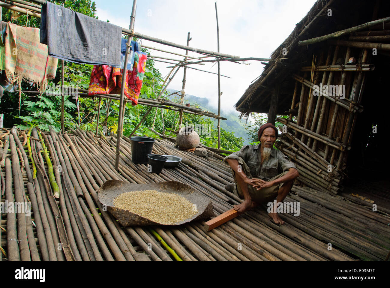 Un vecchio mento uomo seduto di fronte alla propria casa di bambù nel villaggio Kantthar. Foto Stock