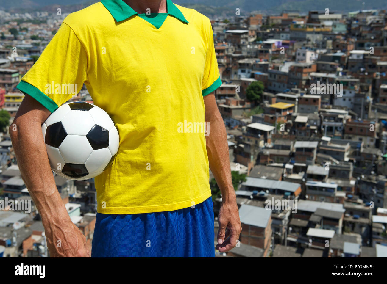 Il calcio brasiliano player in piedi in Brasile colori tenendo palla calcio  nella parte anteriore della favela di sfondo delle baraccopoli di Rio de  Janeiro Foto stock - Alamy