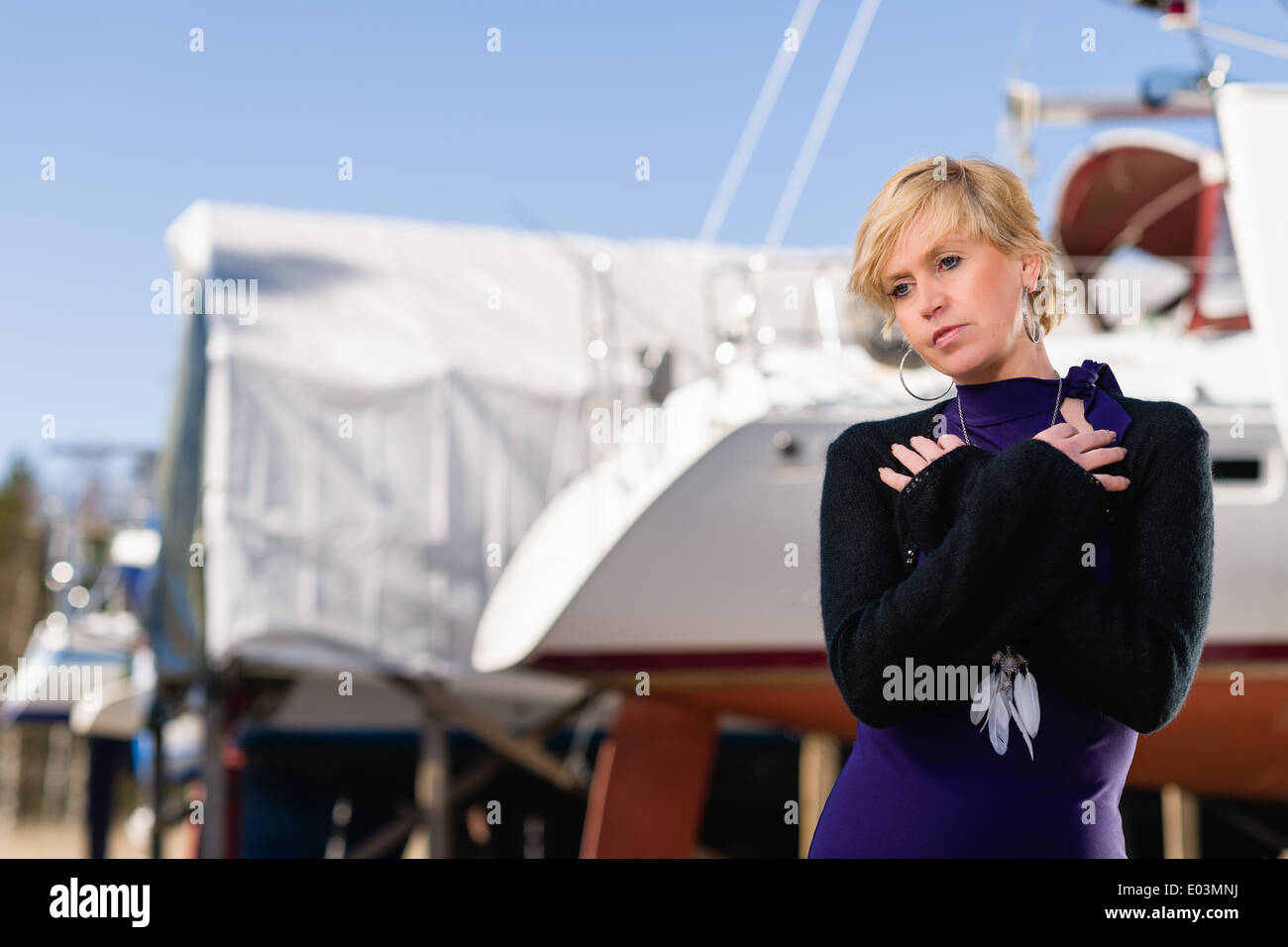 Donna matura indossando abito viola e posa, barca a vela sullo sfondo Foto Stock