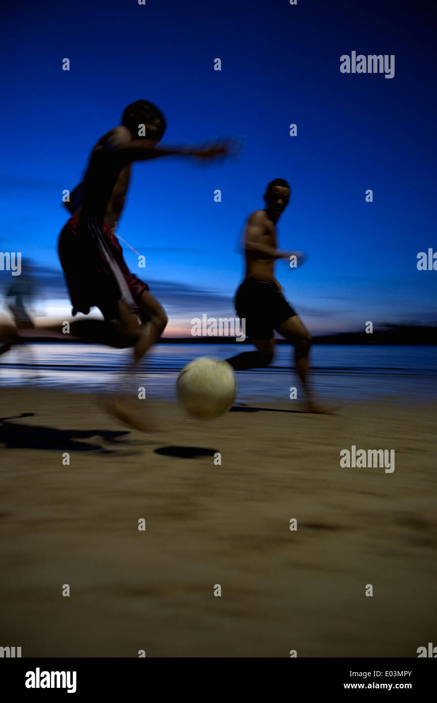 Il calcio brasiliano i giocatori di calcio in esecuzione durante la notte sulla spiaggia in una sfocatura in Nordeste Bahia Brasile Foto Stock