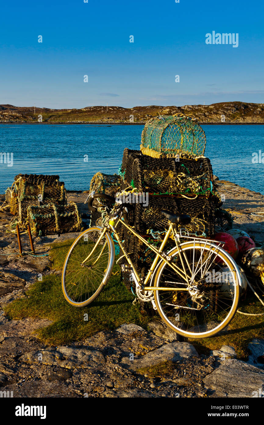Il porto di Arinagour sull'Isola di Coll Ebridi Interne Argyll and Bute Scozia UK con la bici in appoggio contro gli attrezzi da pesca Foto Stock
