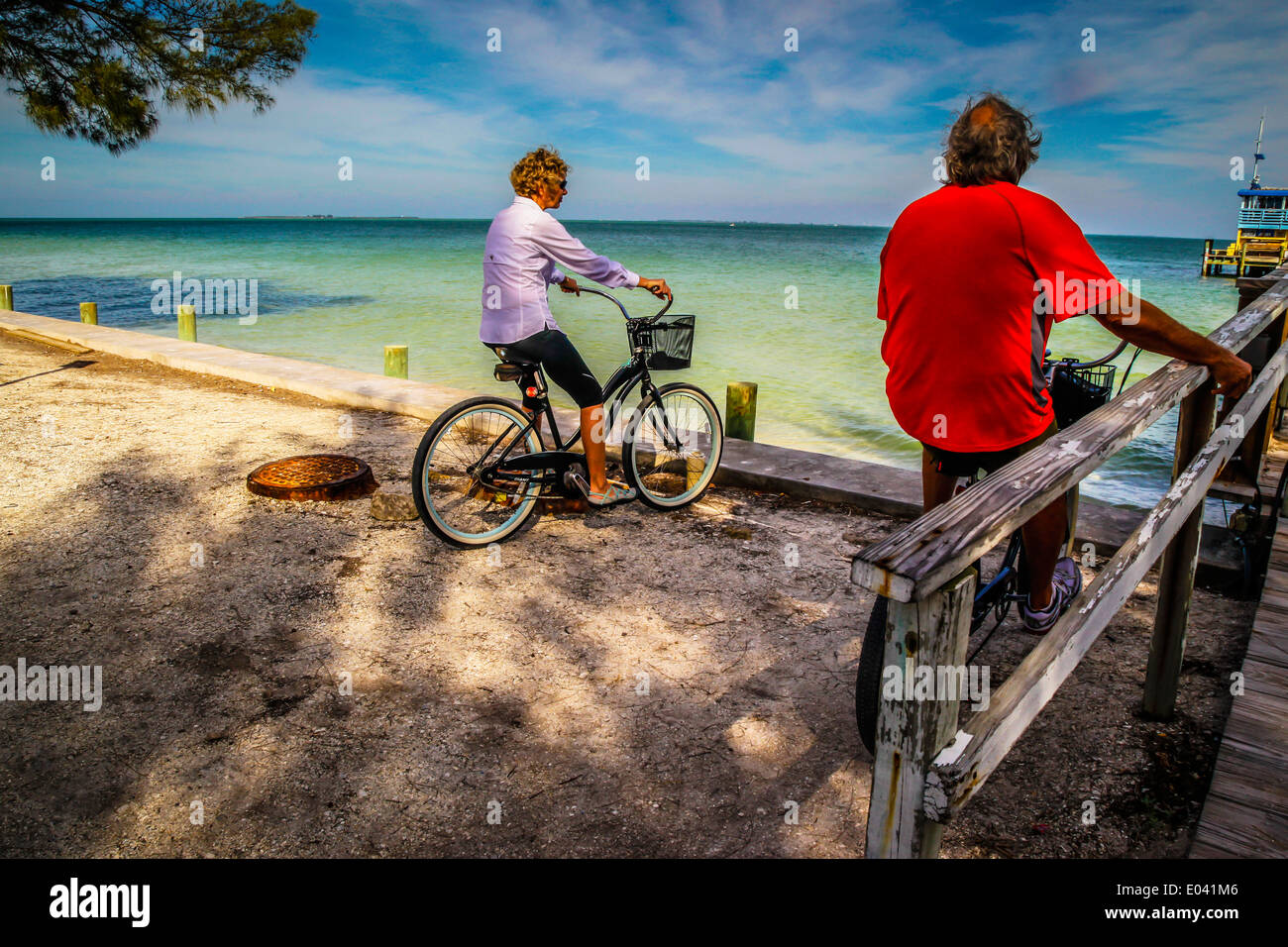 Uomo e donna baby boomer seduto su beach cruiser biciclette, stop per godere della vista mare Foto Stock