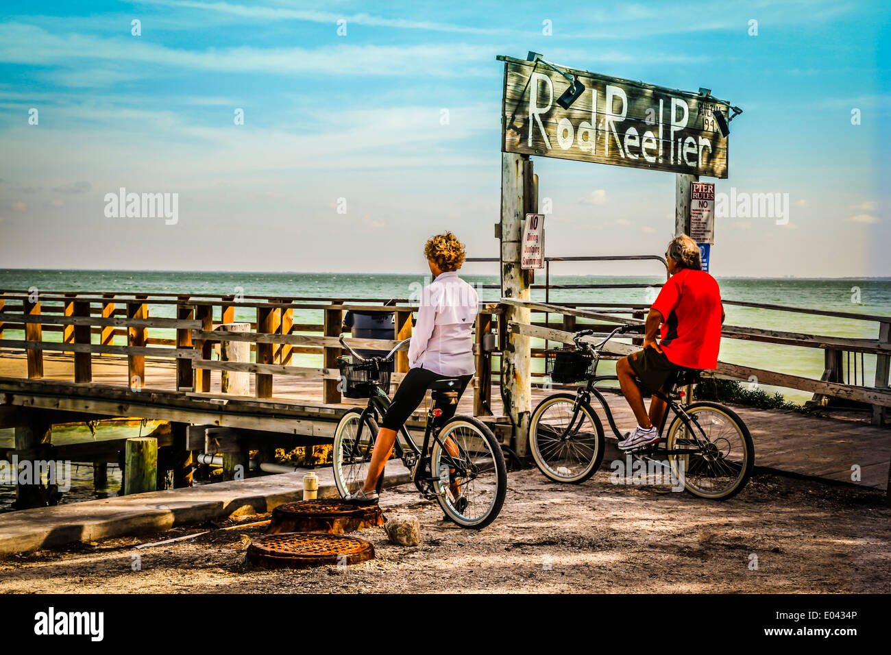 Due persone su biciclette presso la canna e mulinello Pier stop per godersi la vista su Anna Maria Island, Florida Foto Stock