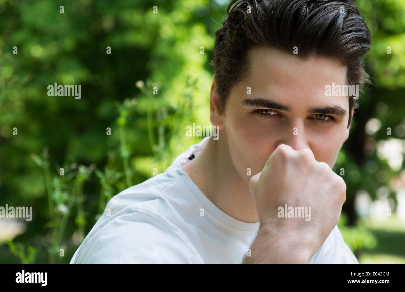 Aggressivo giovane con pugno davanti al suo volto e una sfida guardare negli occhi Foto Stock