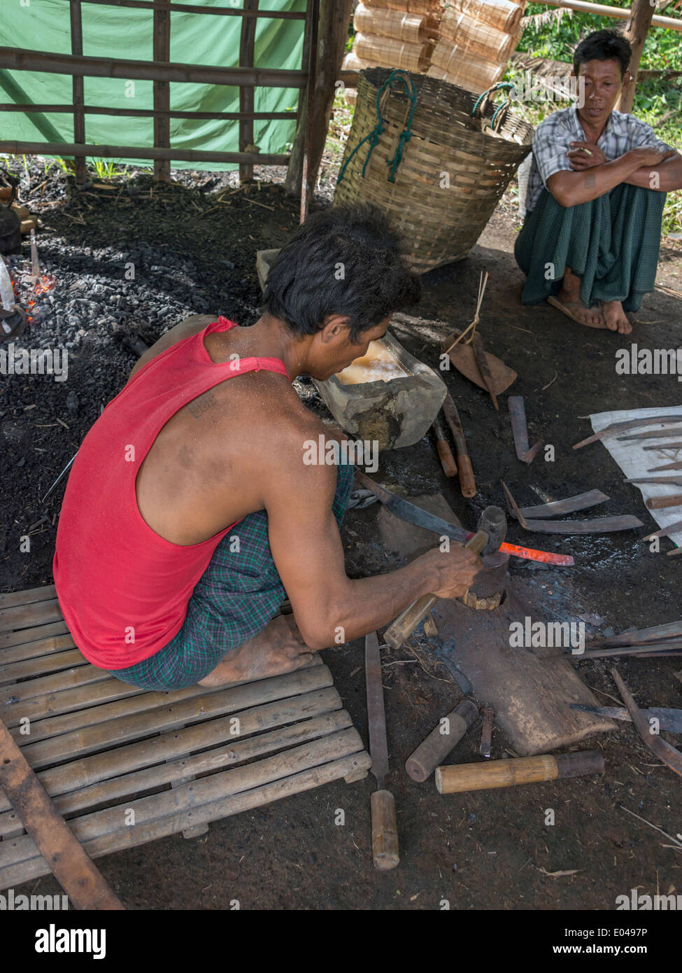 Fabbro pounding un rosso lama calda, Lago Inle mercato, Myanmar Foto Stock