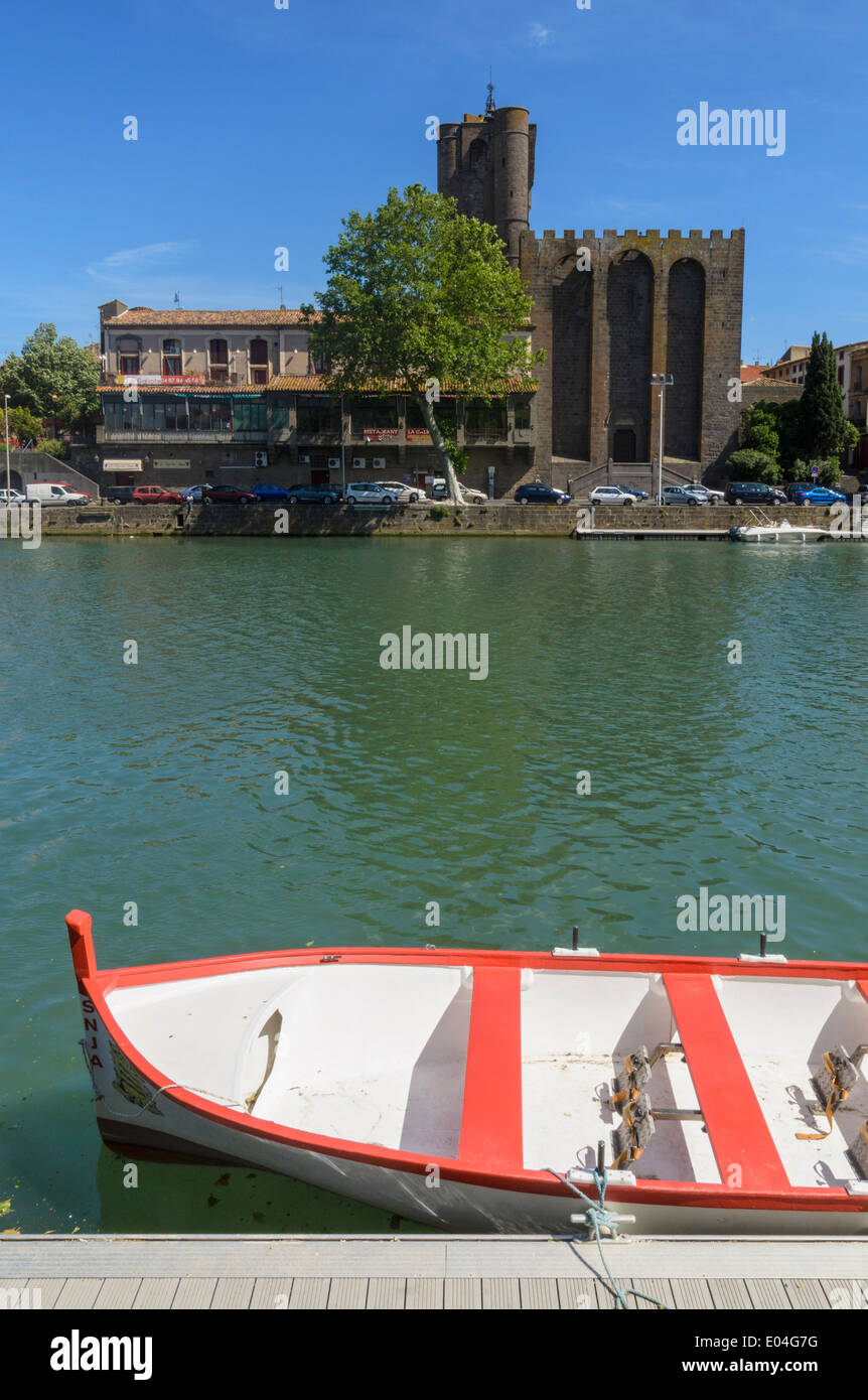 Una piccola barca ormeggiata sul fiume Herault dominato da Agde cattedrale della città di Agde, Herault, Languedoc-Roussillon, Francia Foto Stock