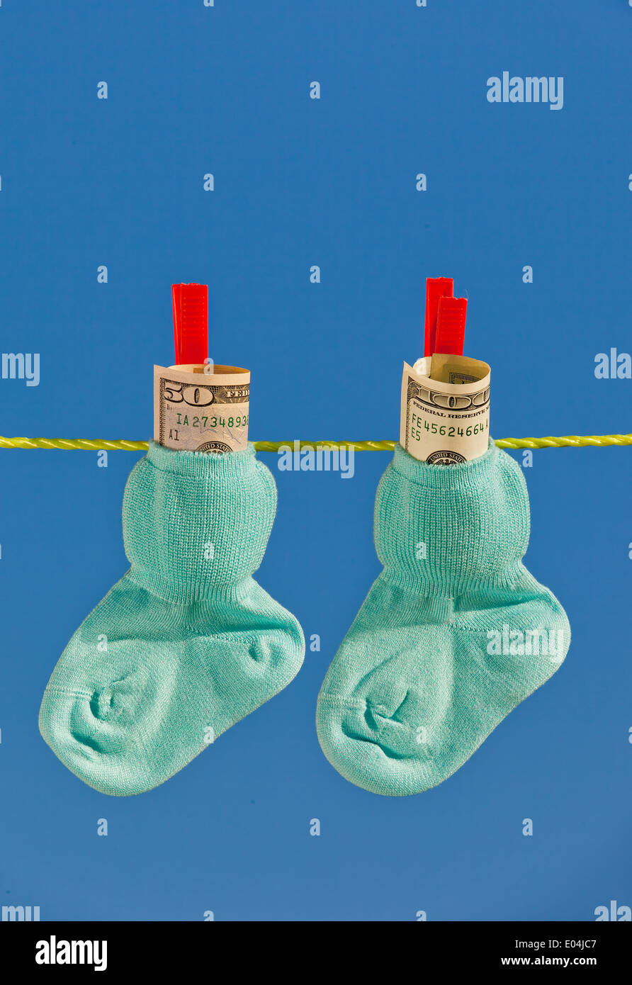 Baby calze su stendibiancheria al secco. Blue sky. con dollari denaro contante Foto Stock