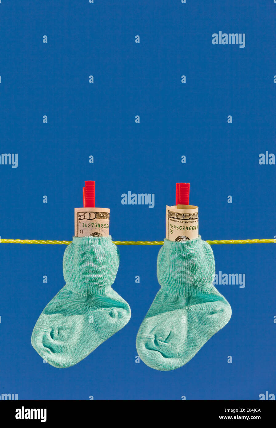 Baby calze su stendibiancheria al secco. Blue sky. con dollari denaro contante Foto Stock