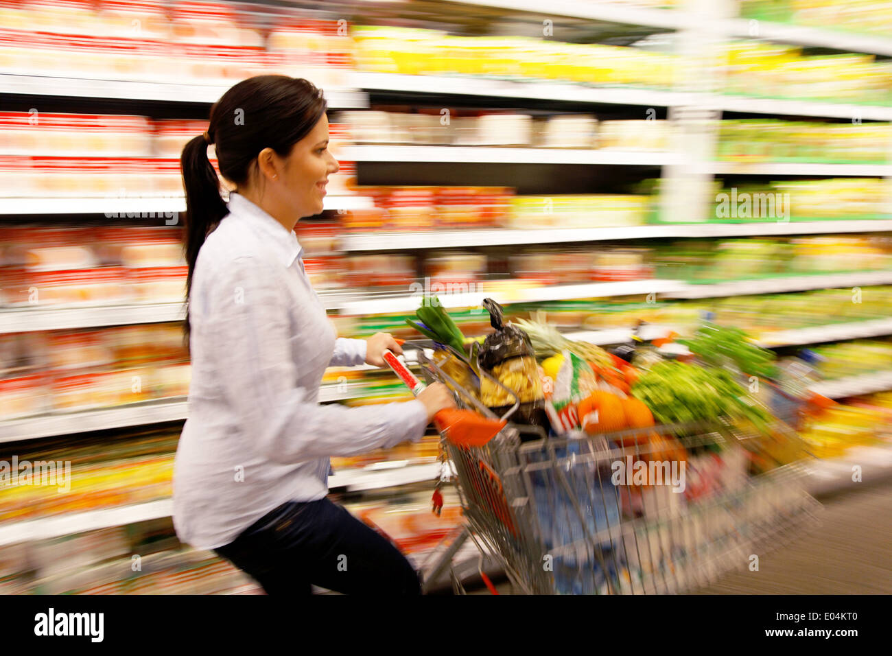 Giovane donna dal carrello al supermercato con l'acquisto, Junge Frau mit Einkaufswagen im Supermarkt beim Einkauf Foto Stock