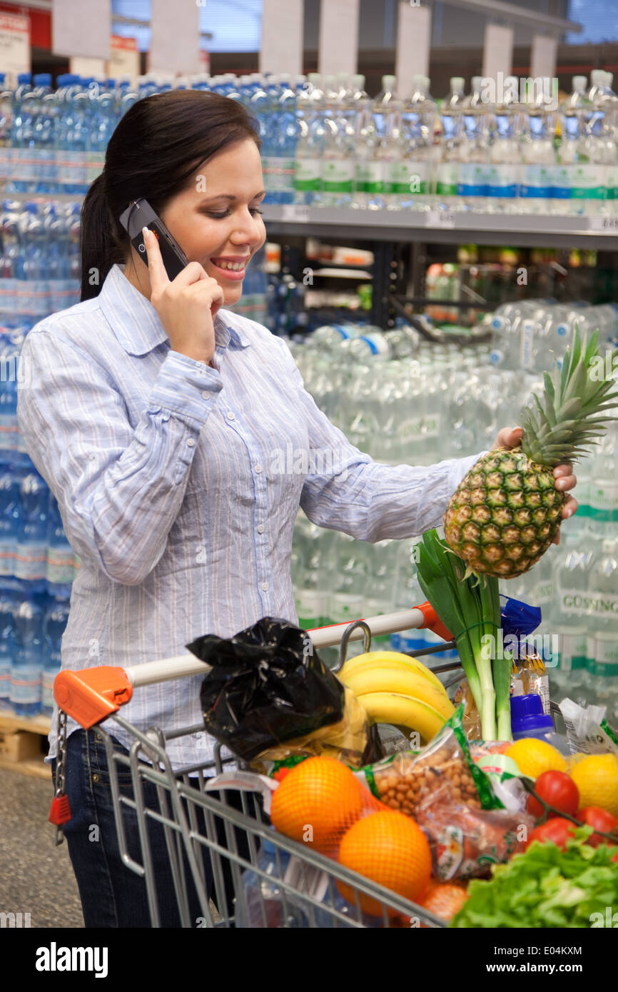 Giovane donna dal carrello al supermercato con l'acquisto., Junge Frau mit Einkaufswagen im Supermarkt beim Einkauf. Foto Stock