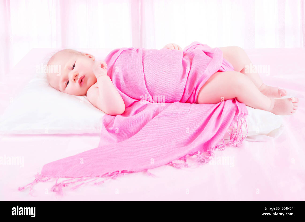 Adorabile bambina sdraiato in camera bambino avvolto in bella coperta rosa, infanzia spensierata, di coricarsi concept Foto Stock