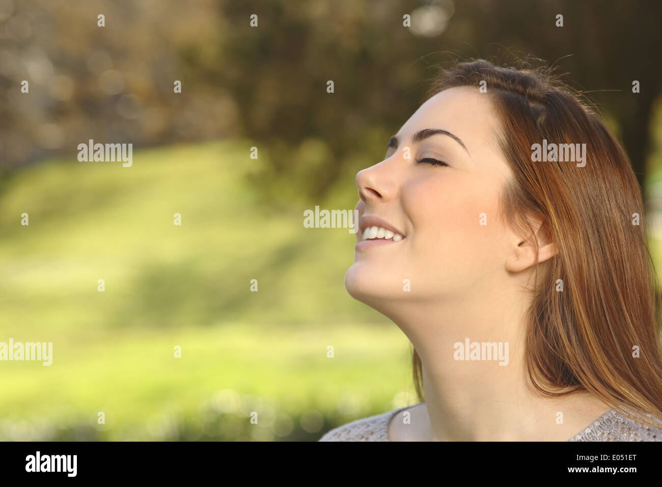 Bella sorridenti donna facendo respirazione profonda esercita in calore park sfondo verde Foto Stock