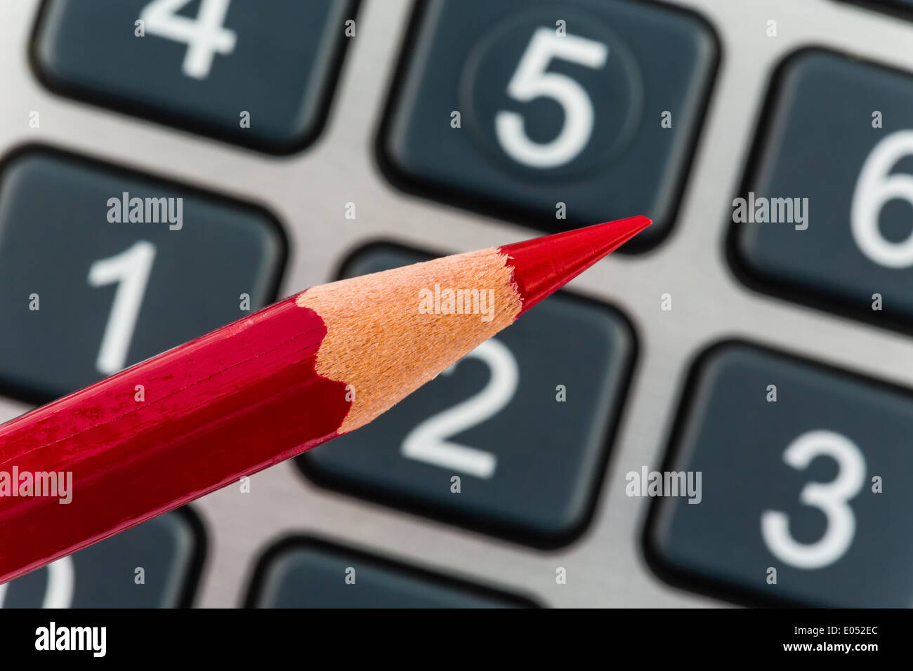 Una matita rossa si trova su di una calcolatrice tascabile. Risparmiare con i costi e i problemi di bilancio a causa della cattiva situazione economica, Ein roter Setif Foto Stock