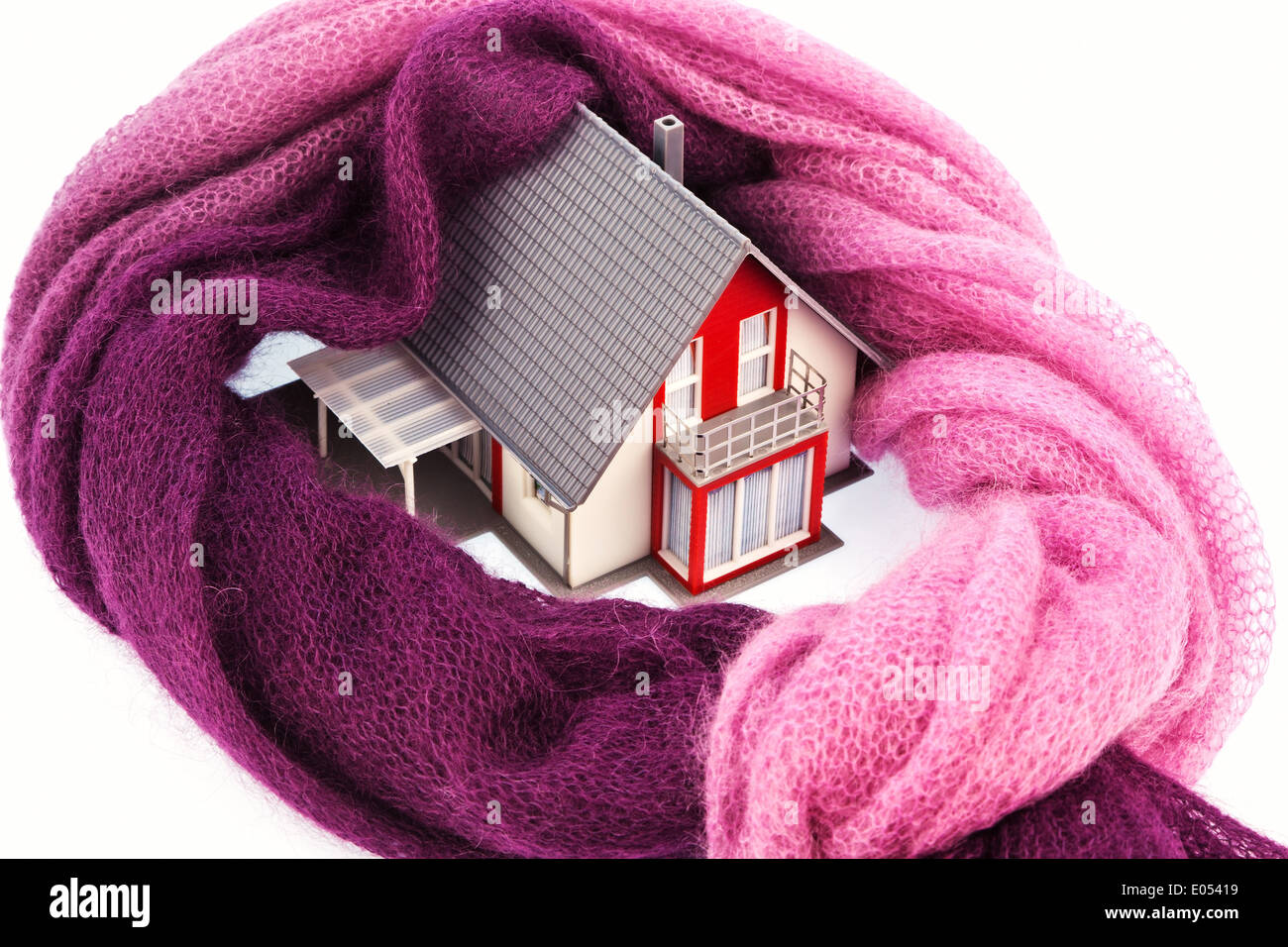 Un modello di casa è avvolto in una sciarpa. Foto simbolico per l'isolamento termico e abbassamento dei costi di riscaldamento., Ein Modell Haus ist Foto Stock