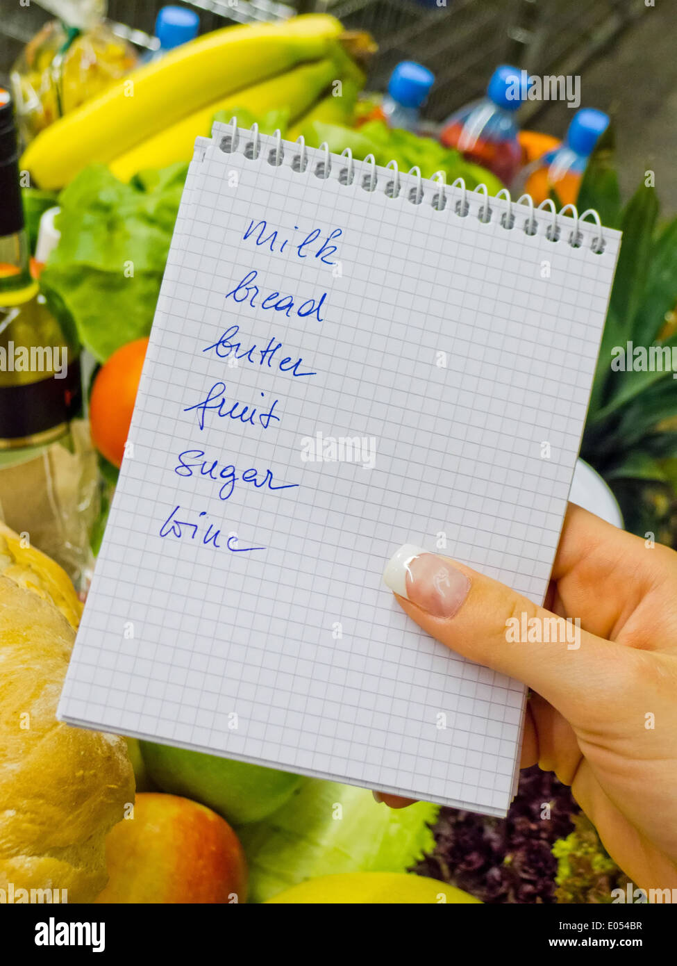 Una donna può contenere un elenco di acquisti in un supermercato in mano. Lingua inglese., Eine Frau hält einen Einkaufszettel in einem supe Foto Stock