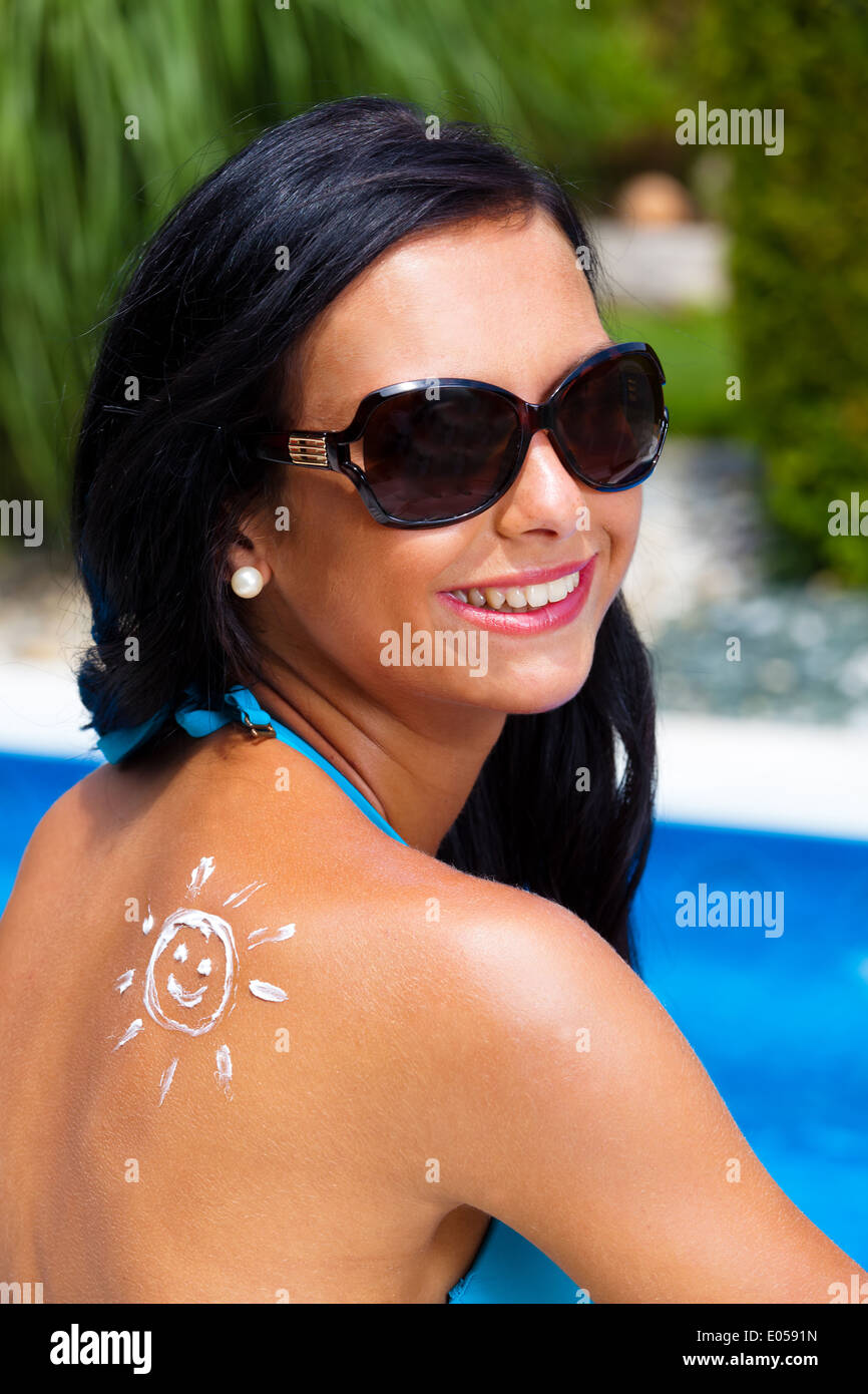 Una giovane donna separa uno con i suns crema. In piscina seduto., Eine junge Frau trennt sich mit Sonnen ein color crema. Foto Stock
