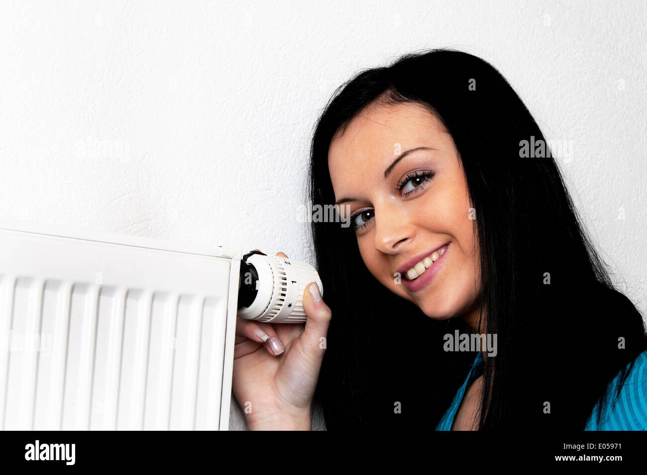 Donna con riscaldatore e termostato di un riscaldamento, Frau mit Heizkoerper termostato und einer Heizung Foto Stock