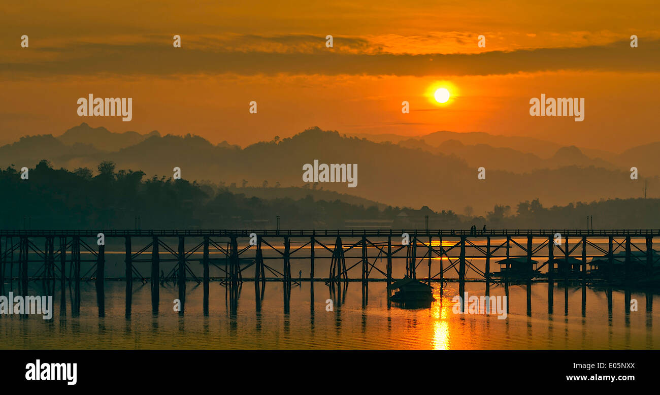 Il sole è in aumento in mattinata dietro il ponte di legno. Foto Stock