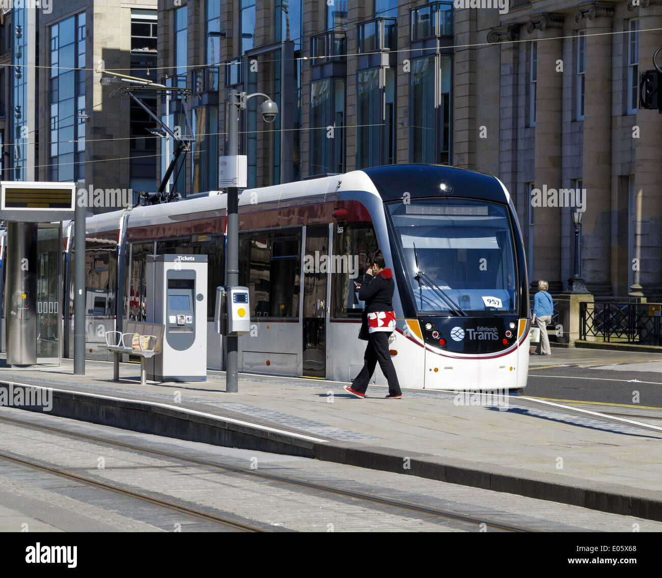Edinburgh tram arrestato in corrispondenza della St Andrew Square stop. Femmina su piattaforma camminando e parlando al cellulare Foto Stock