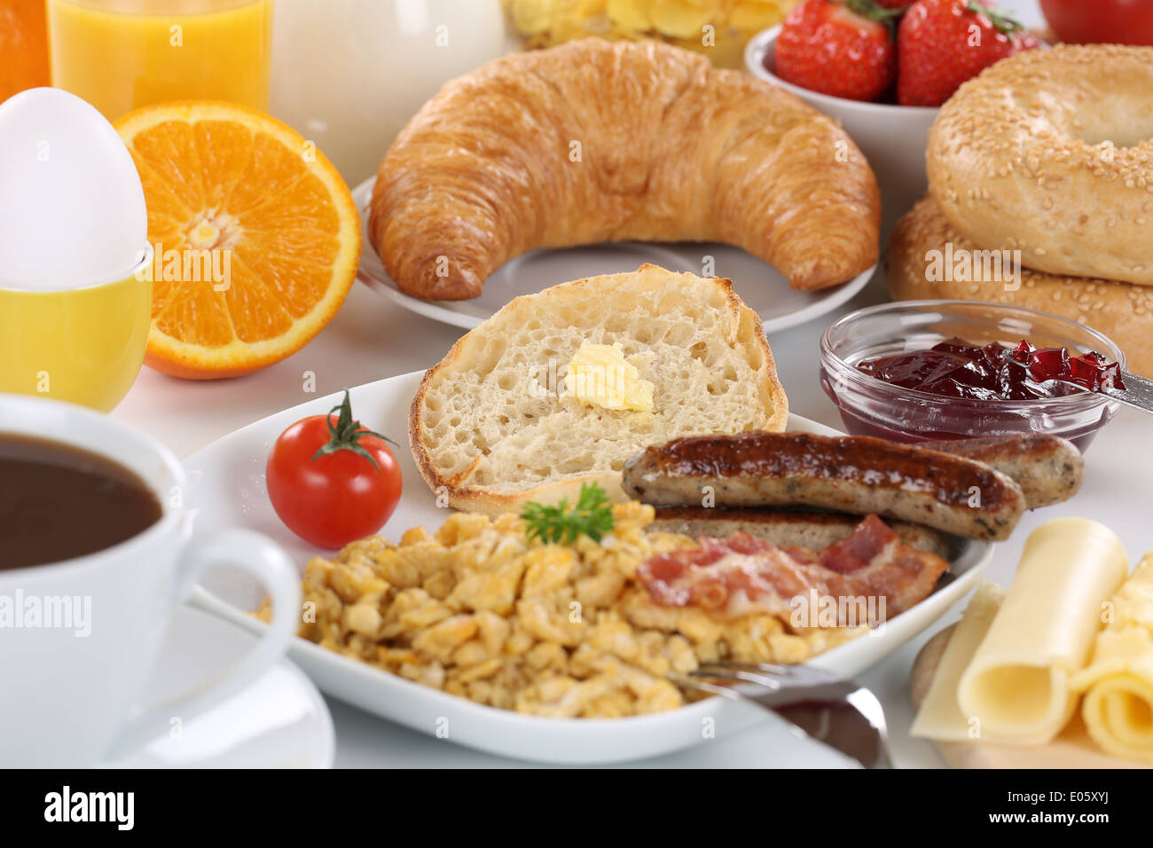 La prima colazione con succo d'arancia, marmellata, caffè, salsiccia, bagels, frutta e uova strapazzate Foto Stock