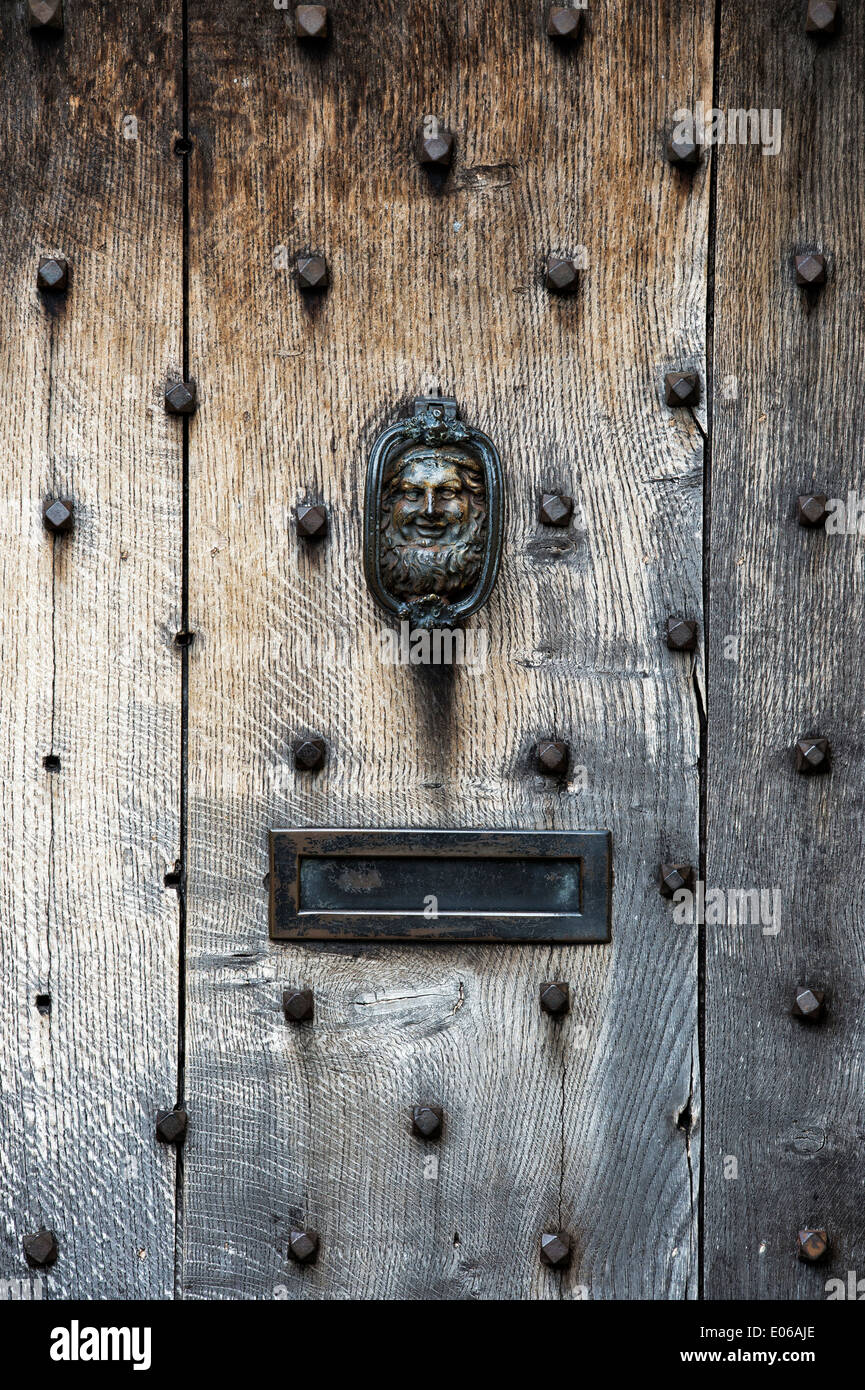 Vecchio ferro battuto porta faccia respingente su una vecchia quercia Legno porta in Cotswolds, Inghilterra Foto Stock