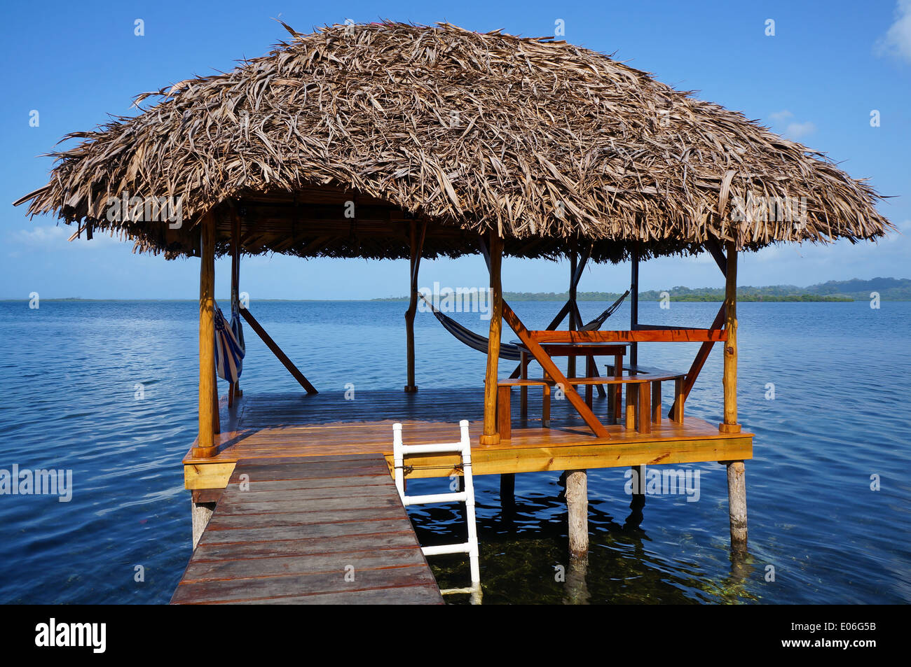 Rifugio tropicale su palafitte sopra l'acqua con tetto di paglia fatta di secche foglie di palma, Mar dei Caraibi Foto Stock