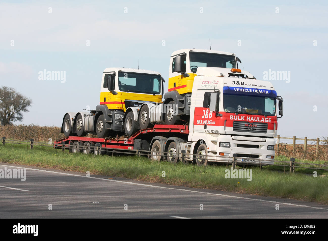 Un J&B Bulk articolati trasporti caricatore basso trasporta due motori del carrello lungo la A417 a doppia carreggiata in Cotswolds, Inghilterra Foto Stock