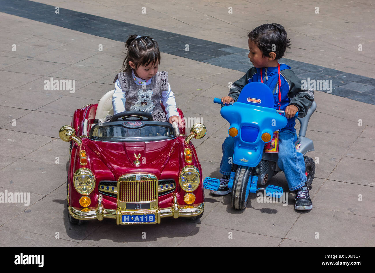 Una classe superiore ragazza boliviana si siede nella sua molto fancy giocattolo telecomandato auto che è ammirato da un povero ragazzo in Sucre, Bolivia. Foto Stock