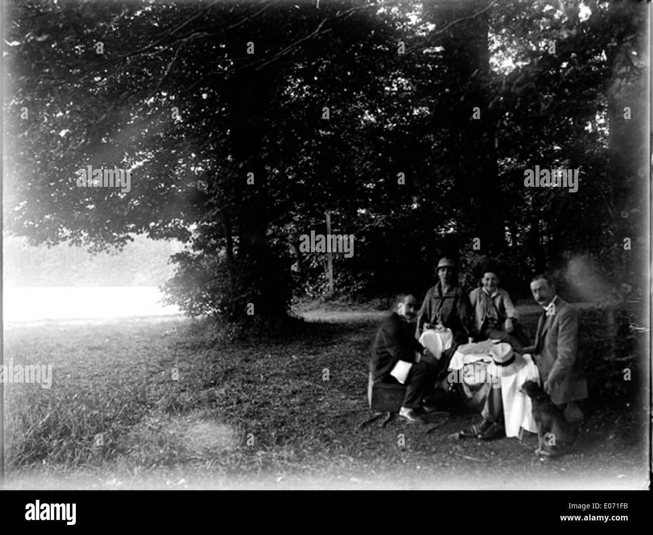 Questo dipinto raffigura un gruppo di persone in una foresta vicino al lago Saint-Ferr in Haute-Garonne, Francia. La scena cattura la bellezza naturale della zona e l'interazione tra le persone e la natura in un ambiente sereno. Foto Stock