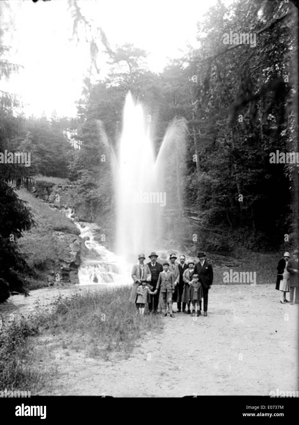 Questa fotografia storica mostra un gruppo di persone che posano di fronte a un geyser all'interno di un'area boschiva, catturata nel XIX secolo. Fornisce uno sguardo sull'esplorazione di fenomeni naturali durante il periodo. Foto Stock