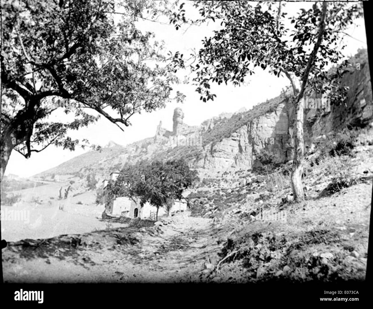 Questa opera d'arte, intitolata "Piton rocheux avec une maison dans les rochers", mostra una collina rocciosa con una casa arroccata in cima. Offre un paesaggio pittoresco, che unisce la robustezza della natura con l'abitare umano. Foto Stock
