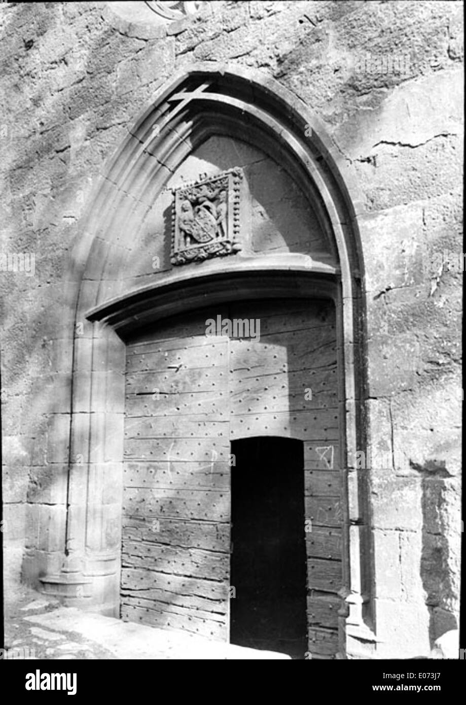 Questa scultura di una porta di casa, caratterizzata da un arco e uno stemma scolpito, si trova nella Bibliothèque de Toulouse, che rappresenta il design architettonico medievale e il patrimonio culturale. Foto Stock