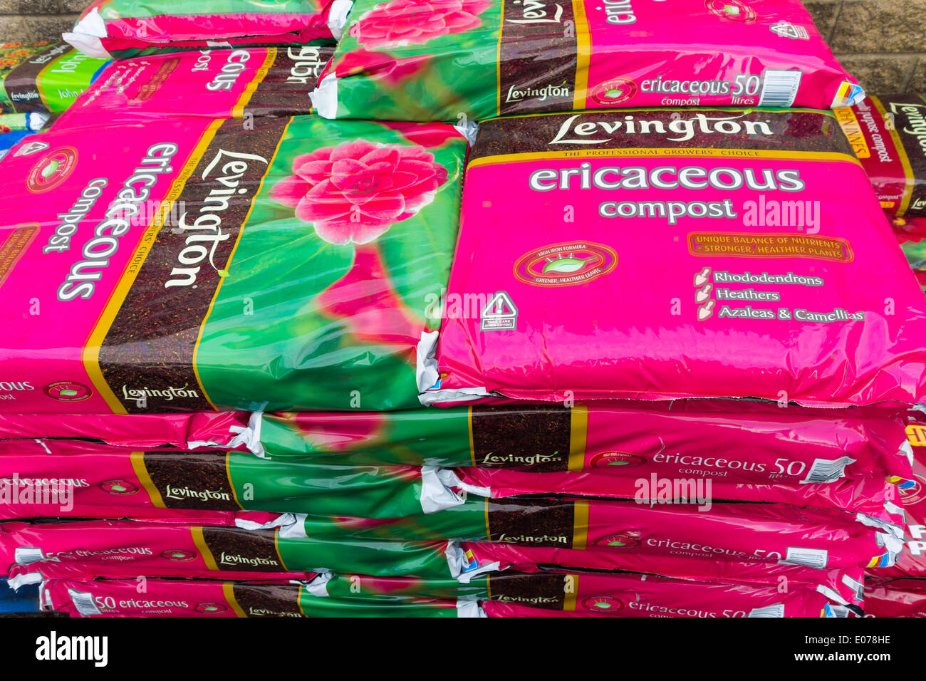Una pila di sacchi di rosa di ericaceous composto in un garden center Foto Stock