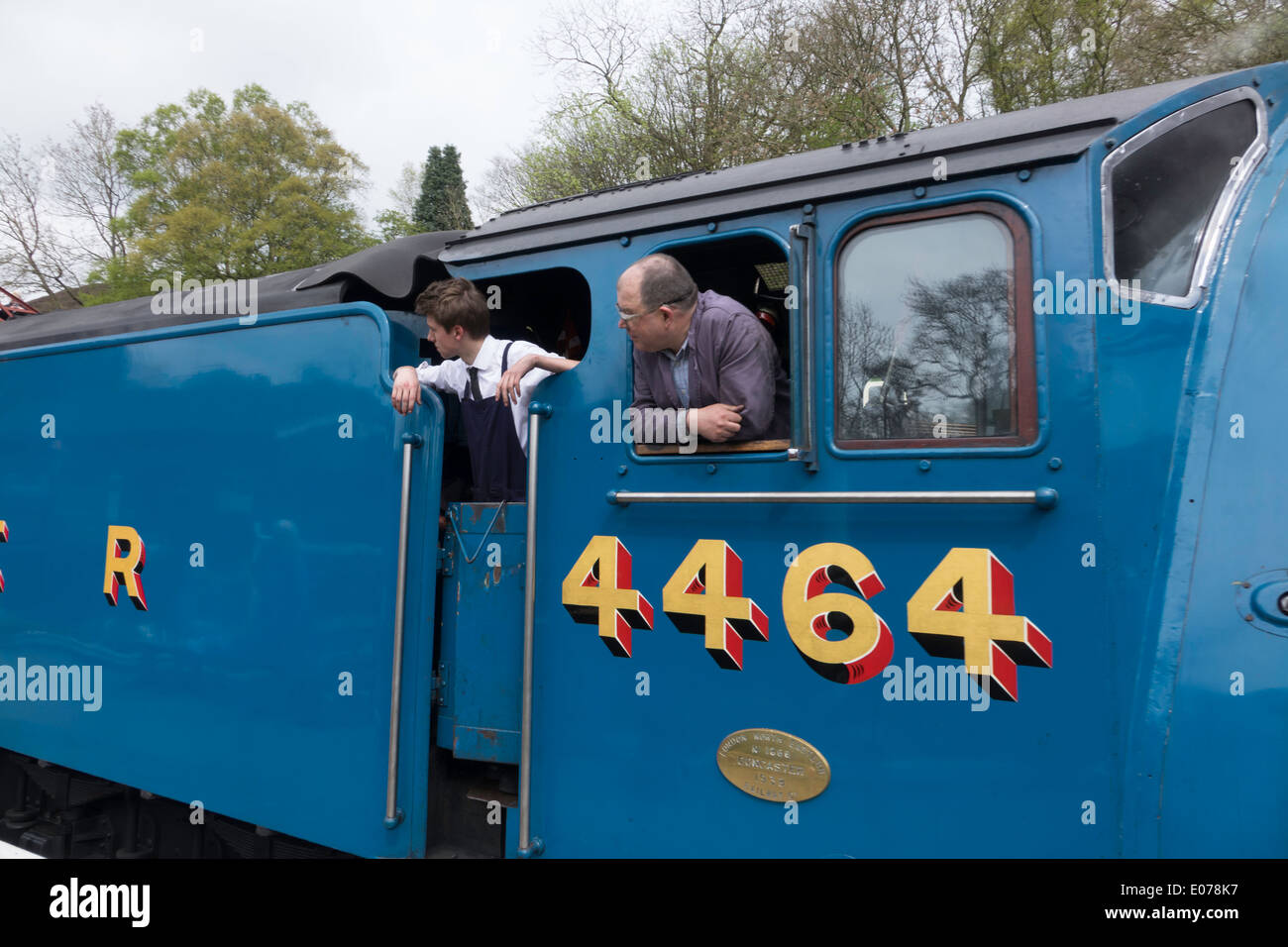 Equipaggio guardare la piattaforma come il treno trainato da Loocomotive 4464 Tarabuso arriva prima gara al NYMR stazione a Goathland Foto Stock