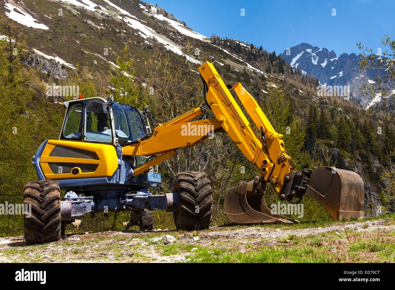 Escavatore giallo lavorare vicino alle montagne Foto Stock