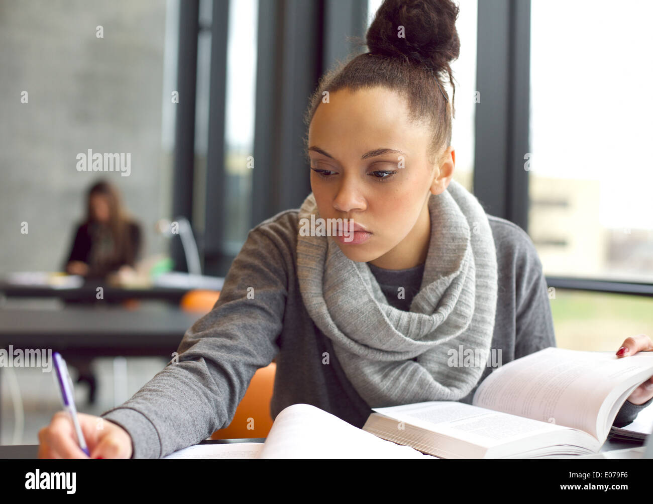 Chiudere l immagine di una giovane studentessa svolgendo incarichi in libreria. Afro American donna prendendo appunti da libri di testo. Foto Stock