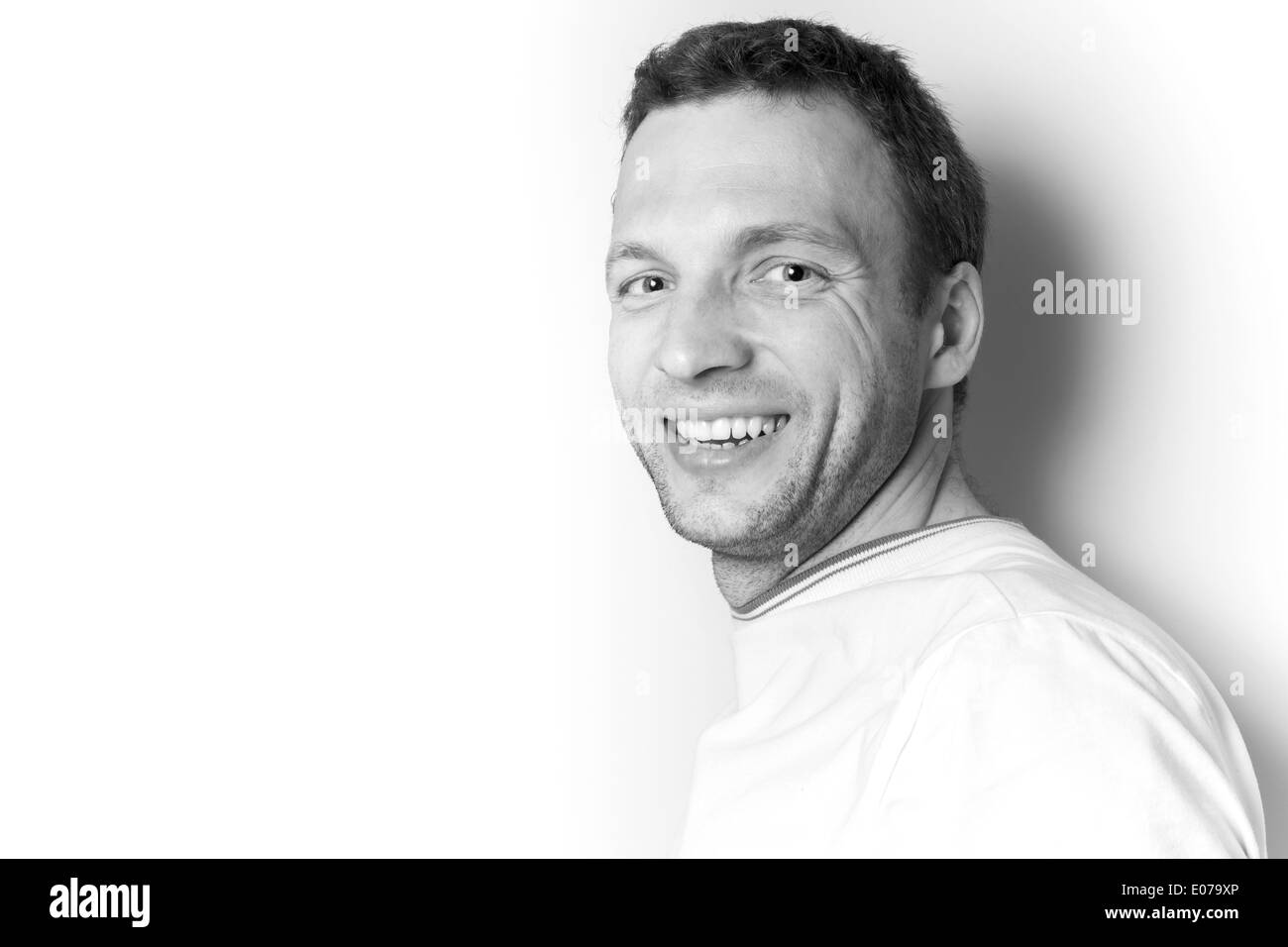 Sorridente giovane uomo caucasico in t-shirt bianco sopra la parete bianca Foto Stock