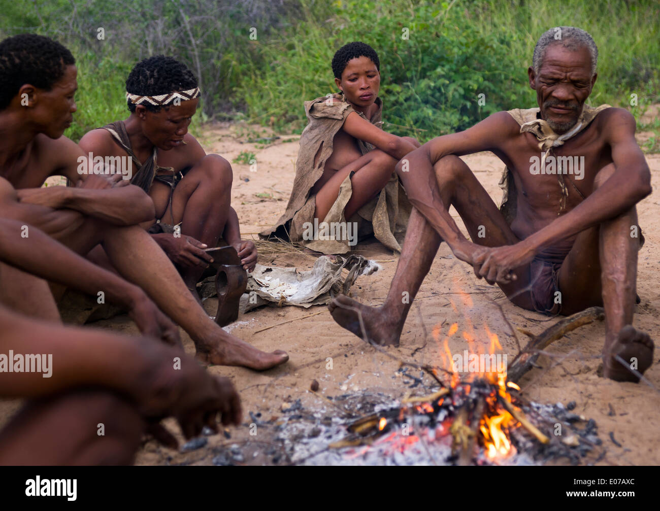 Boscimane di persone attorno a un fuoco in un villaggio tradizionale, Tsumkwe, Namibia Foto Stock