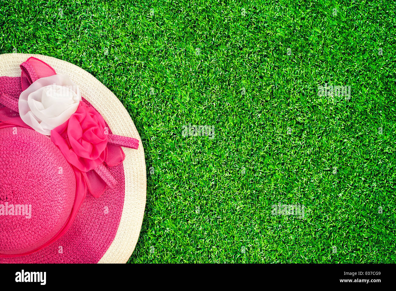 Rosa estate hat con seta rose fiori a una texture verde del giardino di erba. Immagine in stile vintage Foto Stock
