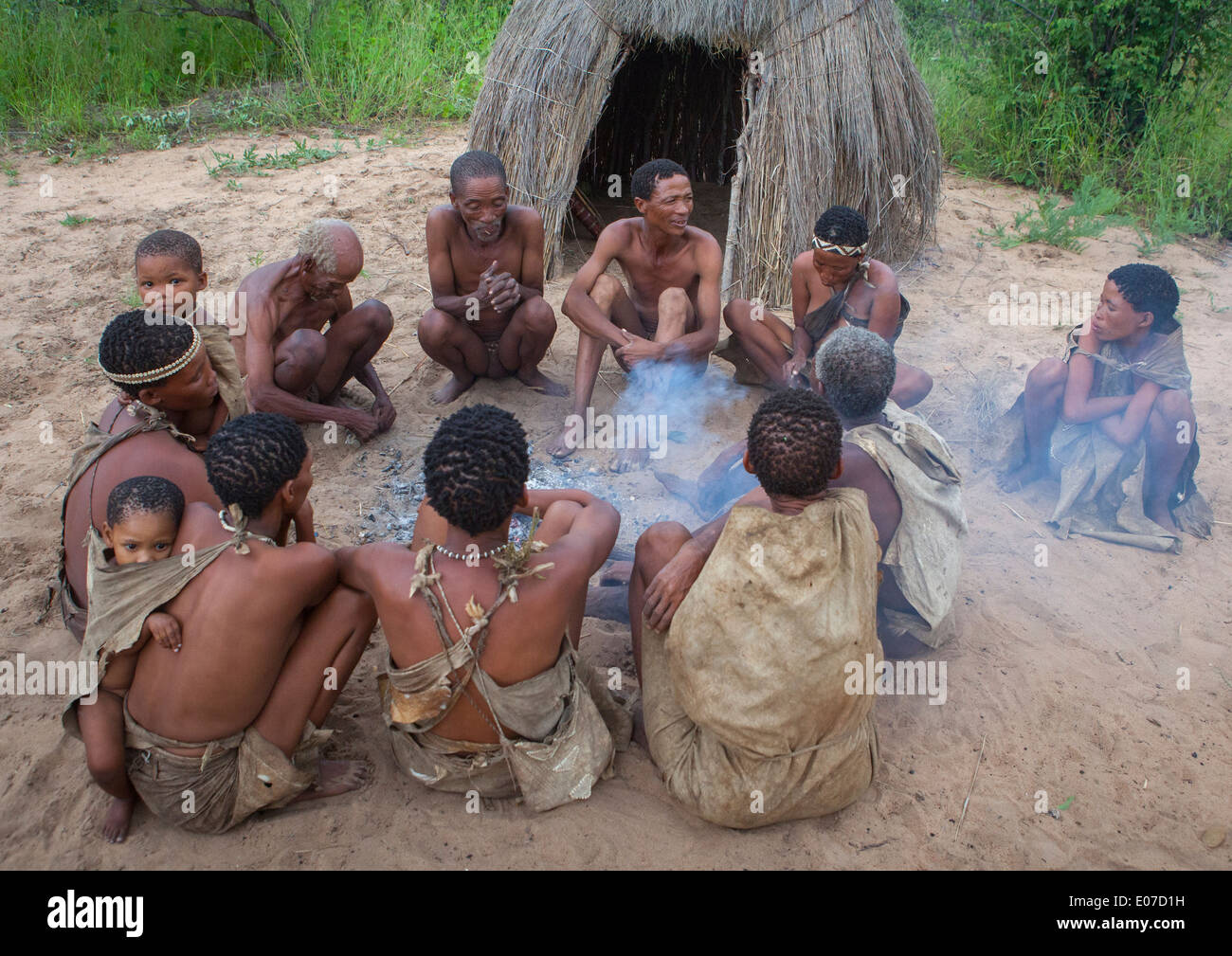 Boscimane di persone attorno a un fuoco in un villaggio tradizionale, Tsumkwe, Namibia Foto Stock