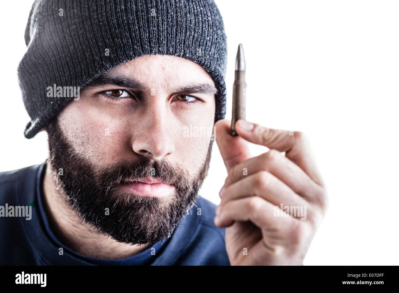 Un uomo barbuto che indossa un beanie hat tenendo un cecchino bullet e lo sta guardando. Isolato su bianco Foto Stock