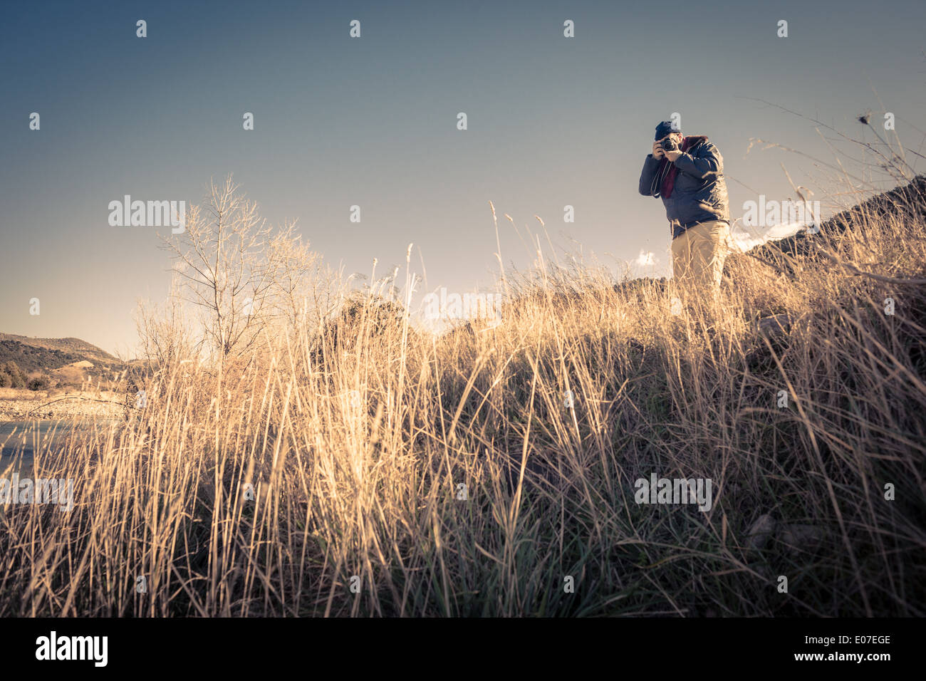 Un uomo di escursionismo e riprese con una fotocamera reflex digitale a obiettivo singolo Foto Stock