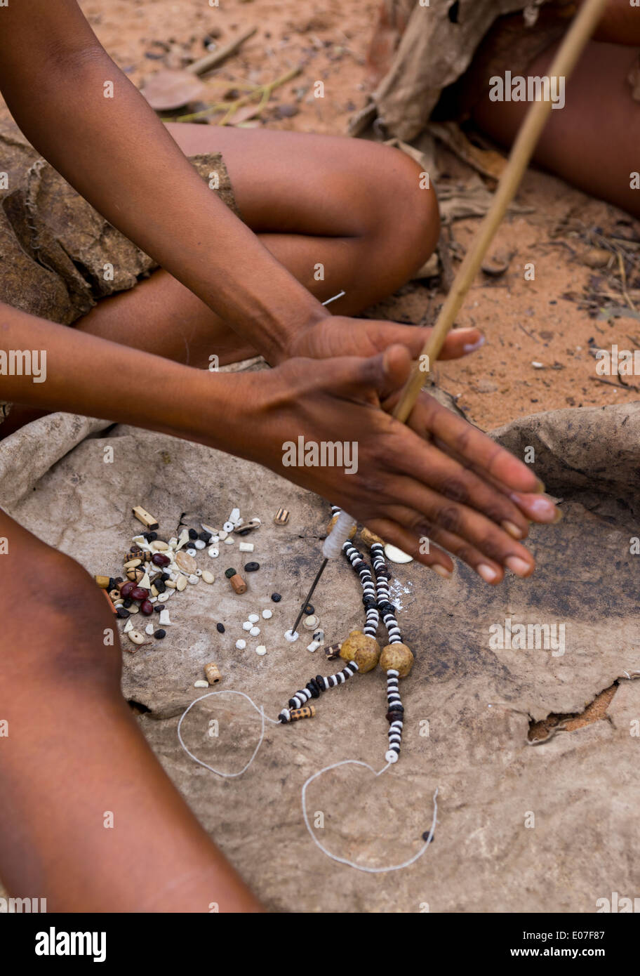 Donna boscimane facendo collane con uovo di struzzo Shell, Tsumkwe, Namibia Foto Stock